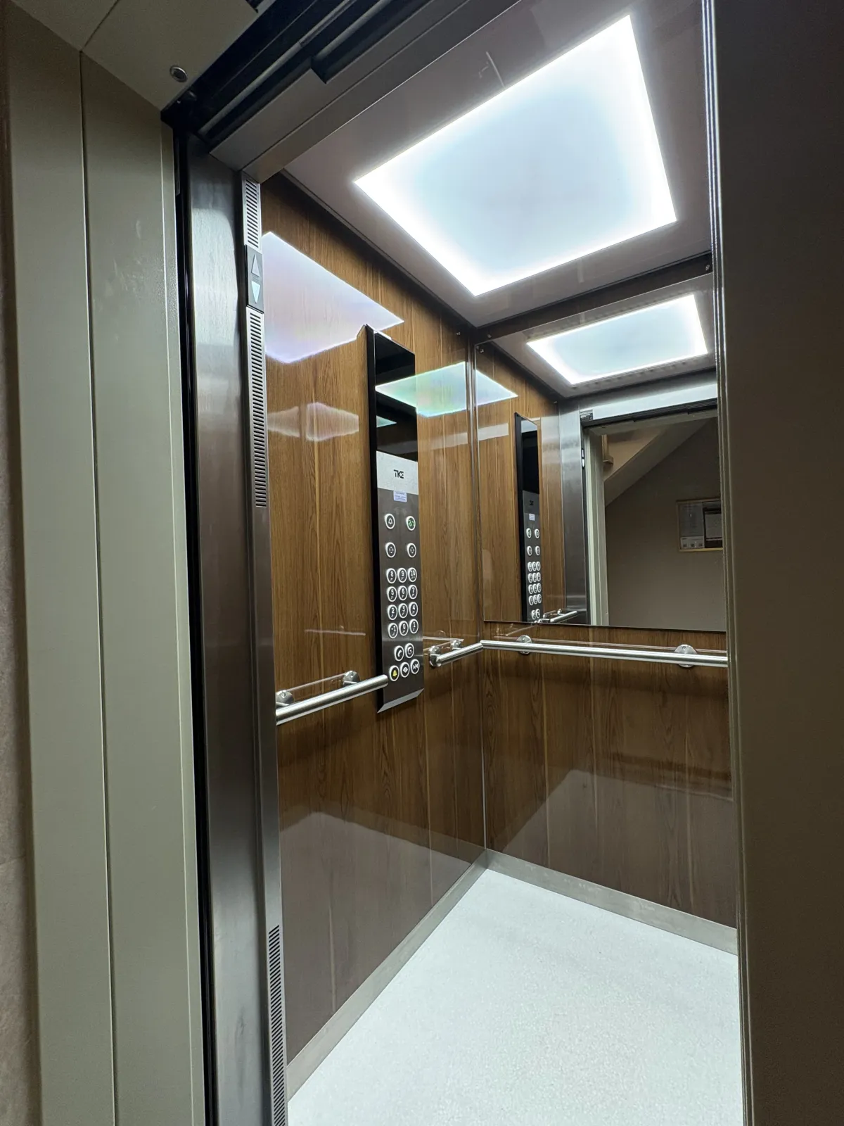 Cabine d'ascenseur rénovée par Kreasteel : habillage bois, éclairage LED et sol clair